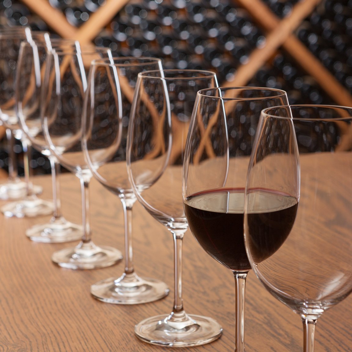 many empty glasses stand in a row, one glass with wine, concept, on the background of shelving